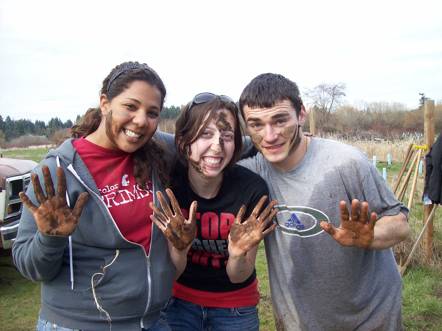 students posing with mud on their hands