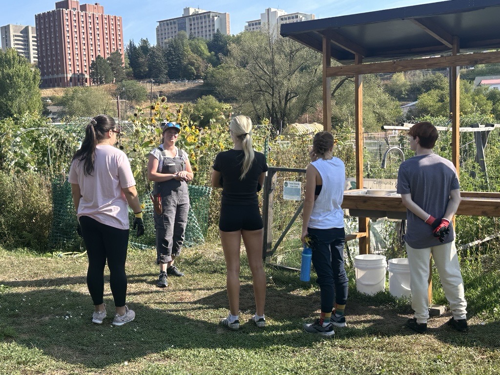 students listen to speaker in front of garden with stephenson tower in background